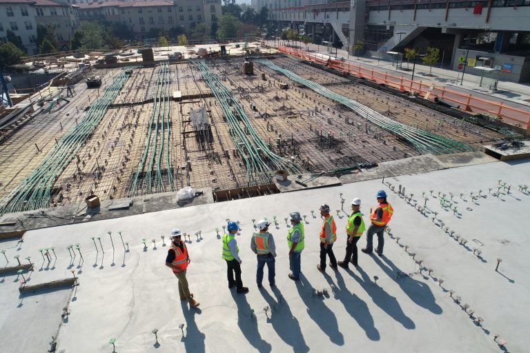 Bauarbeiter in Sicherheitswesten stehen auf einer Baustelle mit Stahl und Beton.